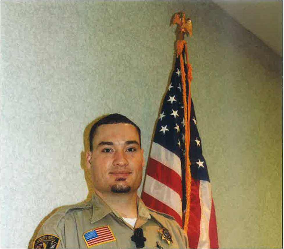 Fallon County Sheriff Trent Harbaugh in uniform with American Flag in the background