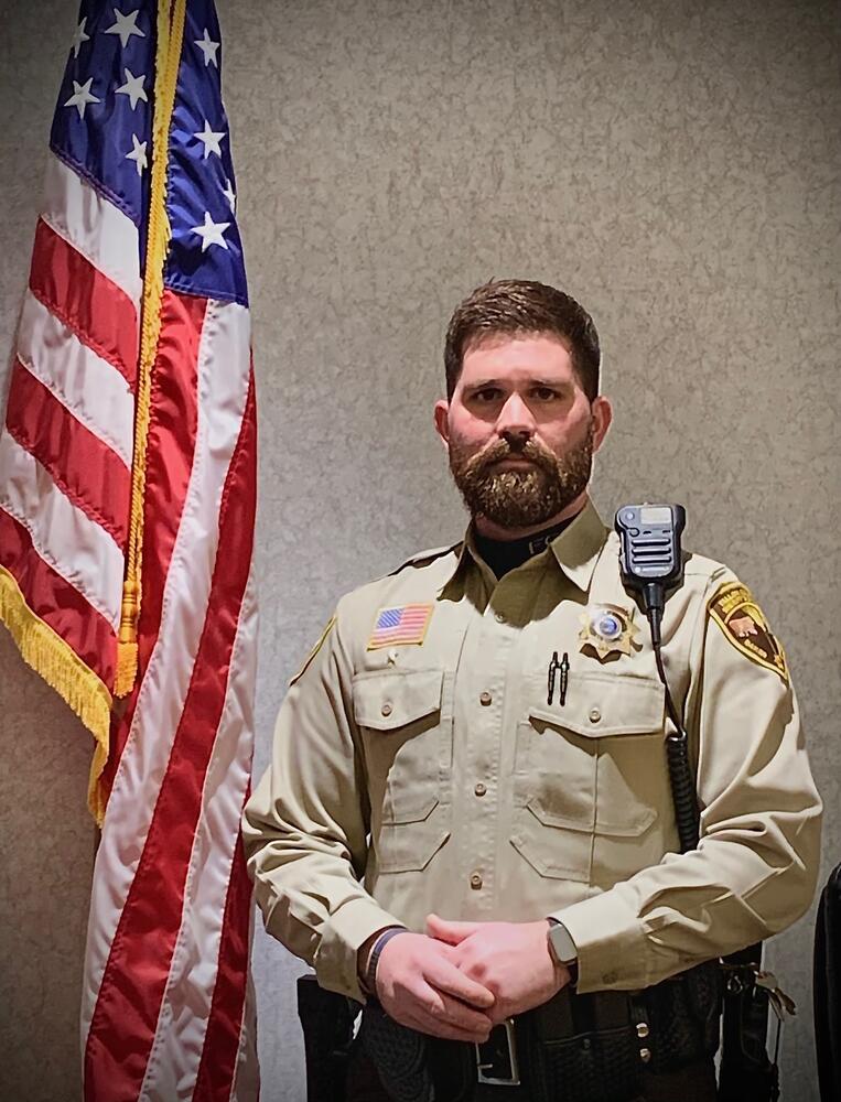 Fallon County Undersheriff Nic Eisele in law enforcement uniform with American flag in the background